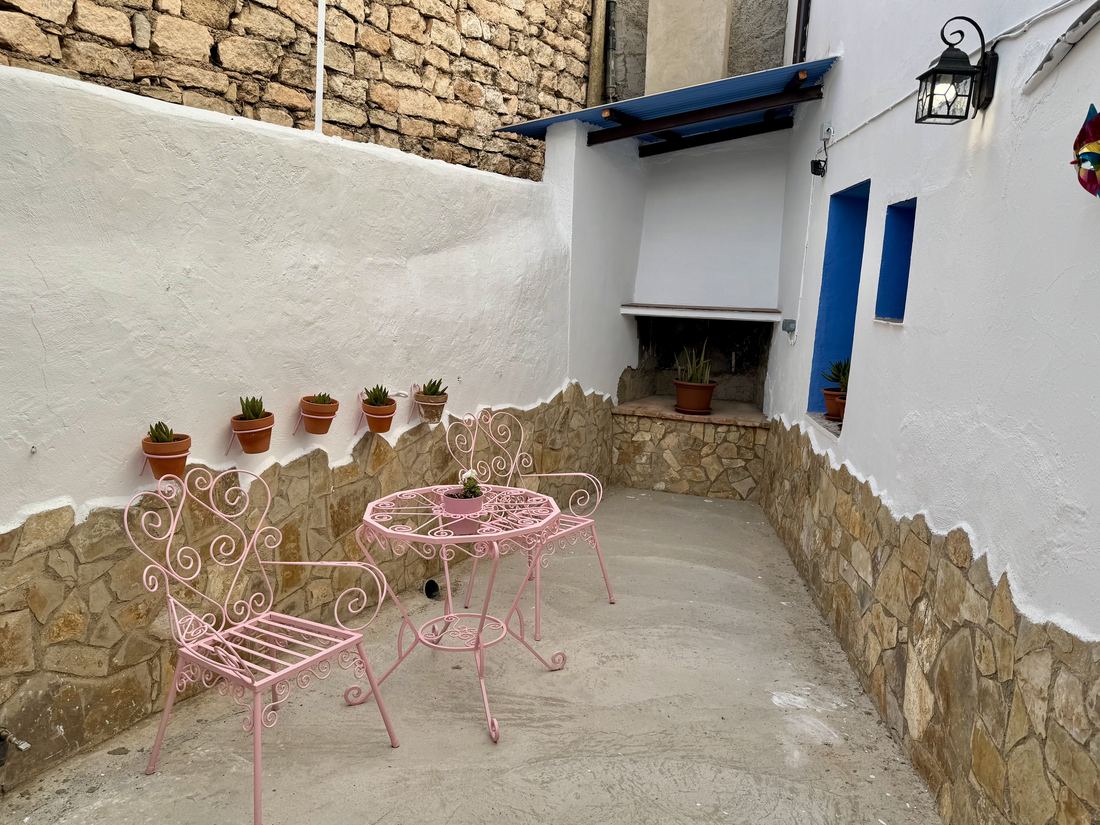 Rincón del asador del corral, con mesa de forja y macetas