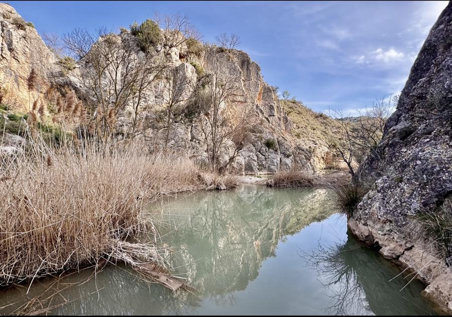 El azud del Huerva entre peñas, con el reflejo del cielo en el agua