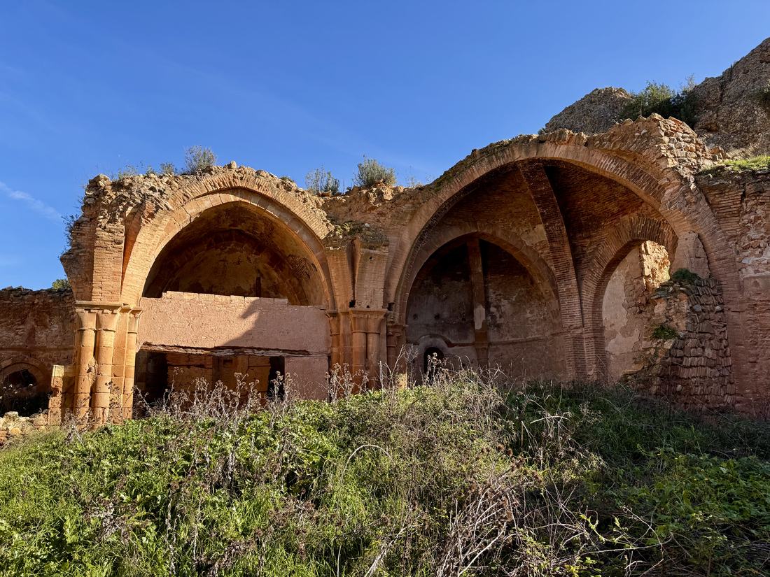 Los arcos apuntados y las bóvedas de crucería de la iglesia gótica del Alcañicejo, abiertos al cielo entre la vegetación