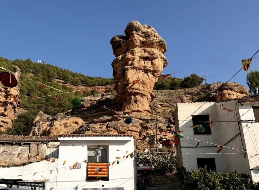 La Peña Chiquita asomando sobre las casas del pueblo en fiestas, con guirnaldas y banderas de Aragón