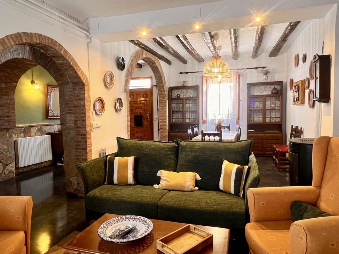 Salón San Bartolomé, zona de estar con sofá verde y arcos de ladrillo